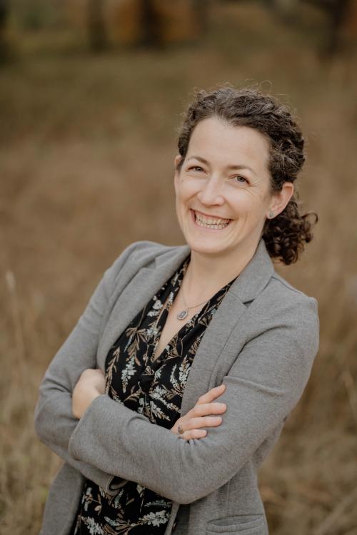 Smiling woman in a grey blazer.